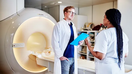 Medical staff talking in front of an MRI machine.