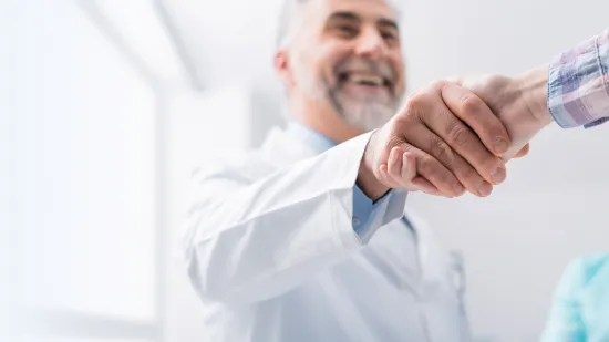 Ein freundlicher Arzt schüttelt einem Patienten die Hand.
